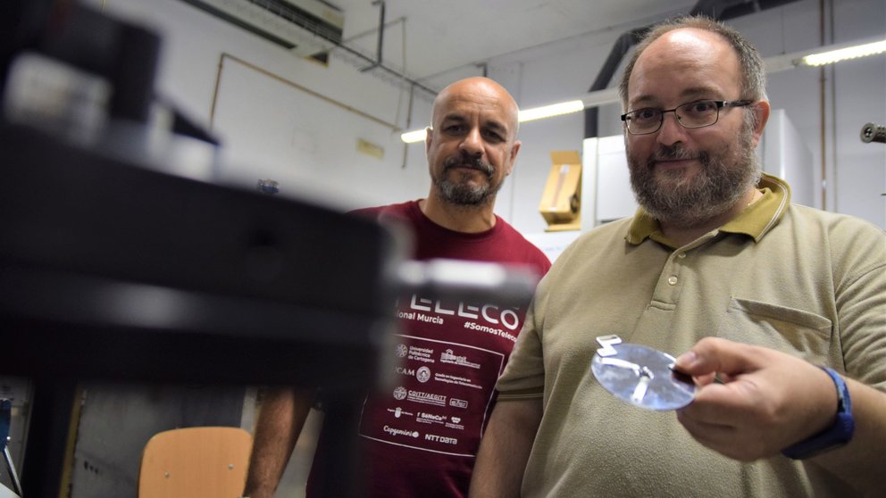 los investigadores José Abad y Juan Francisco González con una muestra de un chip de silicio junto a un microscopio de fuerza, en un laboratorio de la Escuela de Telecomunicación de la UPCT.