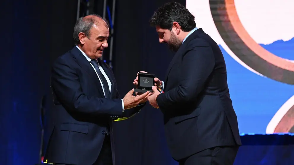 El presidente de UCOERM, Juan Antonio Pedreño (izq.) entrega la insignia a López Miras