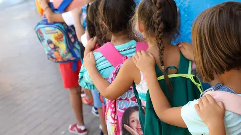Varios ni&ntilde;os hacen fila con sus mochilas